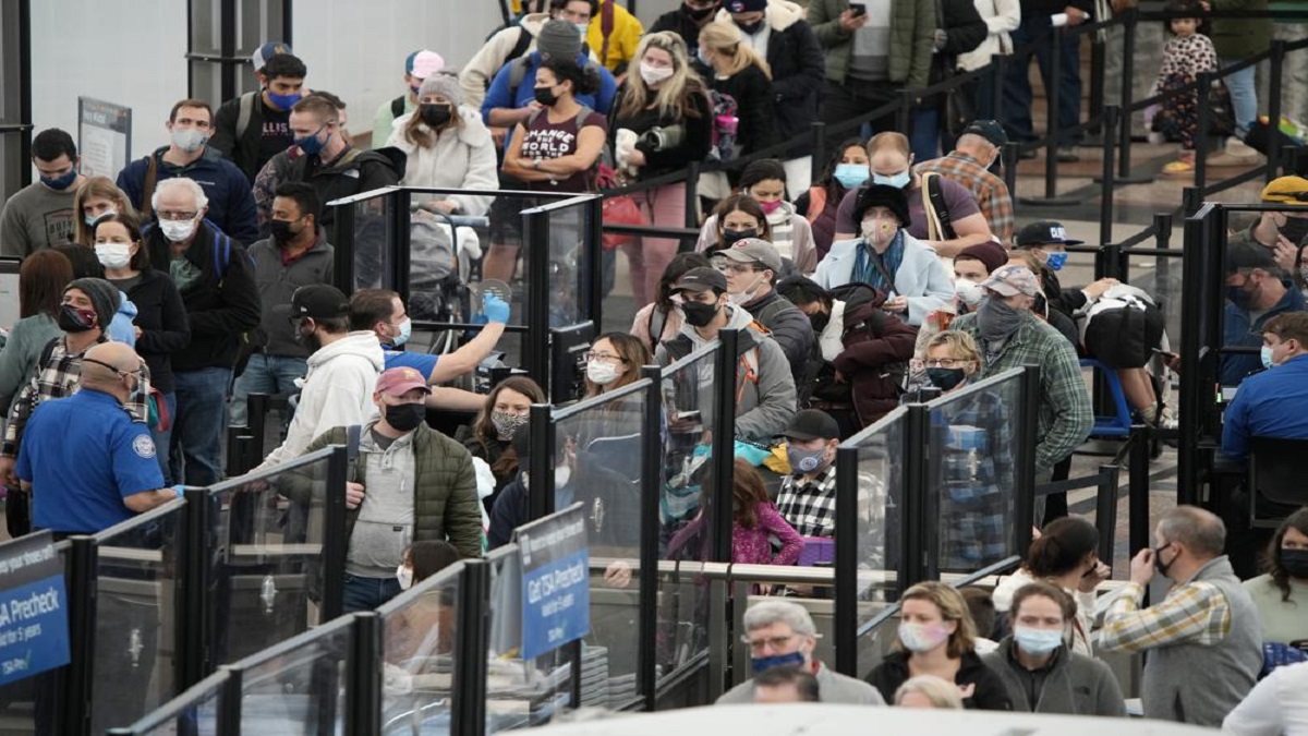 Passengers queue up to pass through the north security checkpoint Monday, Jan. 3, 2022, in the main terminal of Denver International Airport in Denver.