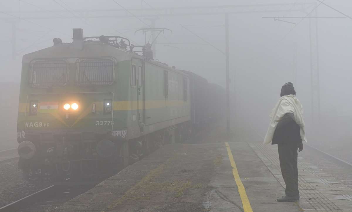 Gautam Buddha Nagar: A man looks on as a goods train approaches the Maripat railway station, amid low visibility due to fog on a cold winter morning