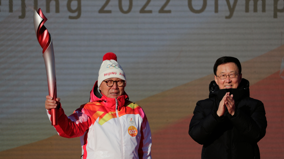 First Torch bearer Luo Zhihuan holds up the torch after receiving it from Chinese Vice Premier Han Zheng before the start of the torch relay for the 2022 Winter Olympics at the Olympic Forest Park in Beijing. (File photo)