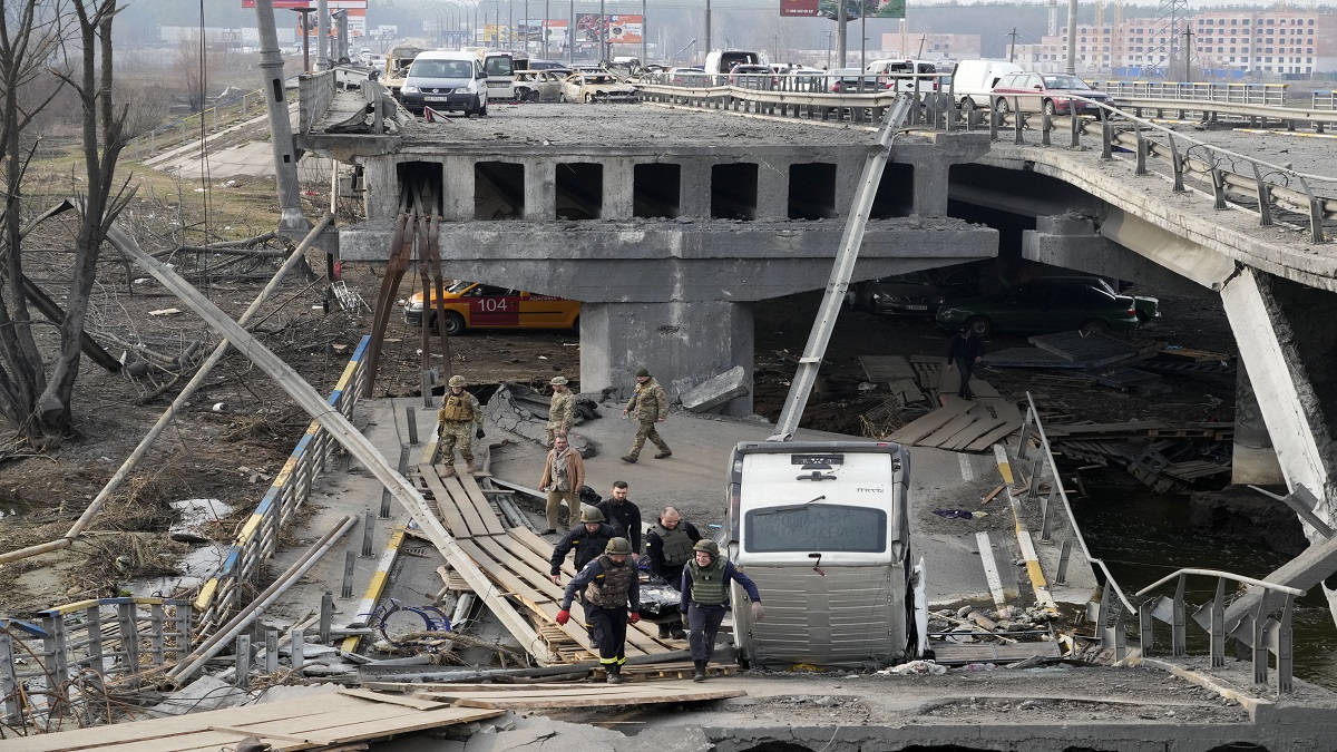 Ukrainian soldiers carry a body of a civilian killed by the Russian forces over the destroyed bridge in Irpin close to Kyiv, Ukraine, Thursday, March 31, 2022.