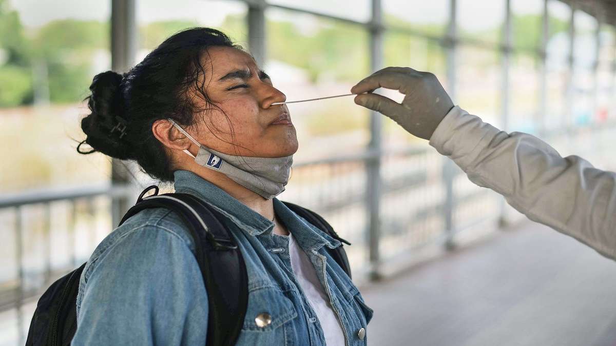 A medic collects swab sample of a commuter for Covid-19 test.