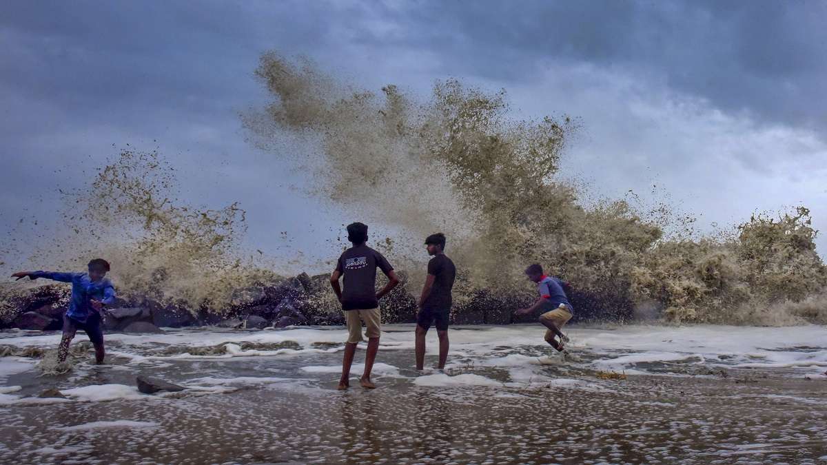 Children play as sea waves lash shore during monsoon season in Kochi
