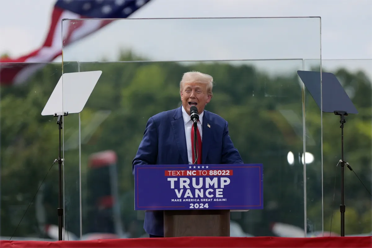 Republican presidential nominee former President Donald Trump speaks behind a bulletproof glass during a campaign rally at the North Carolina Aviation Museum.