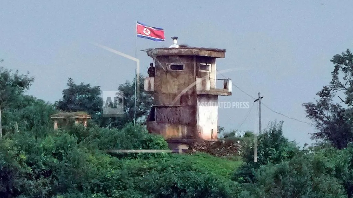 A North Korean soldier stands at the North's military guard post as a North Korean flag flutters in the wind, in this view from Paju, South Korea
