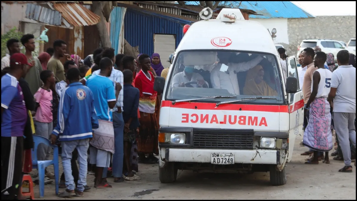 People gather as an ambulance carries the dead bodies after the terror attack in Somalia's Lido beach.