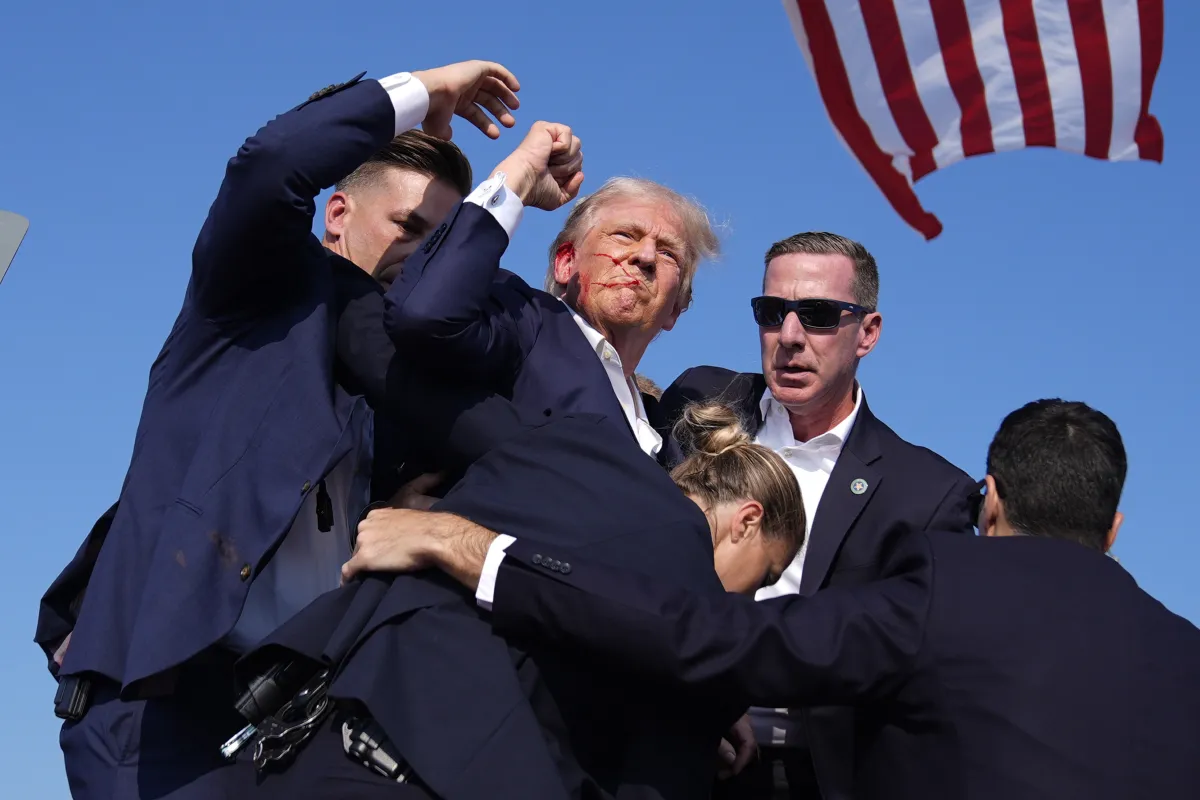Republican presidential candidate former President Donald Trump is surrounded by US Secret Service agents at a campaign rally, July 13, 2024,