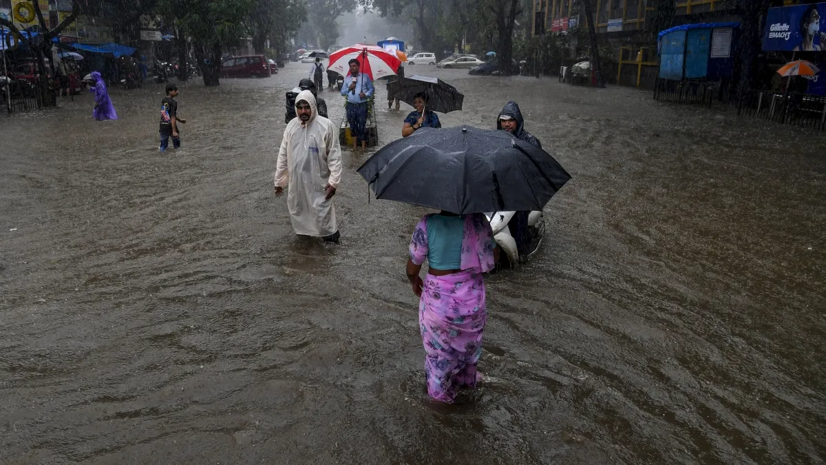 Commuters make their way through a waterlogged road amid rainfall in Mumbai