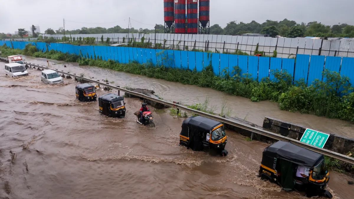 Commuters wade through a waterlogged road following rainfall, near Navi Mumbai International Airport, Monday, Aug. 18, 2025.