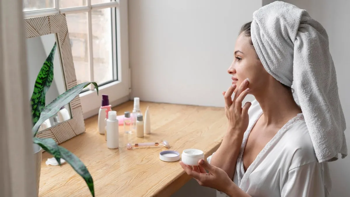 A simple morning skincare routine with the right products helps manage oily skin effectively Woman with towel-wrapped hair applying face cream as part of morning skincare routine for oily skin