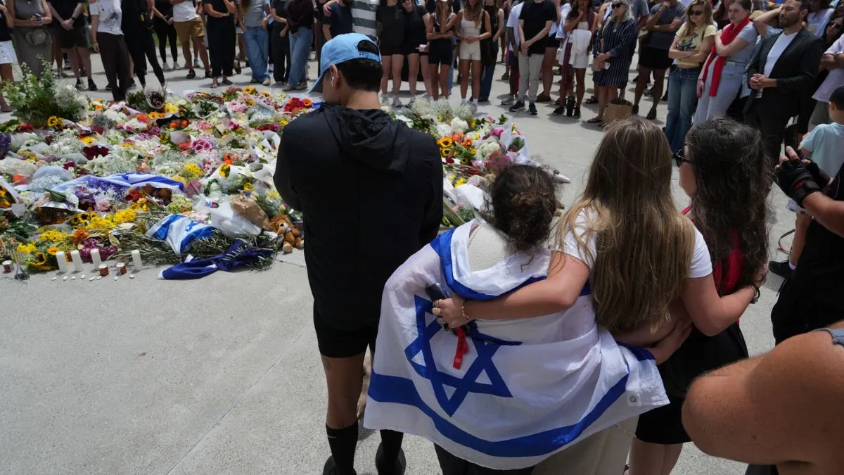 People gather around a growing flower tribute to shooting victims outside the Bondi Pavilion at Sydney's Bondi Beach.