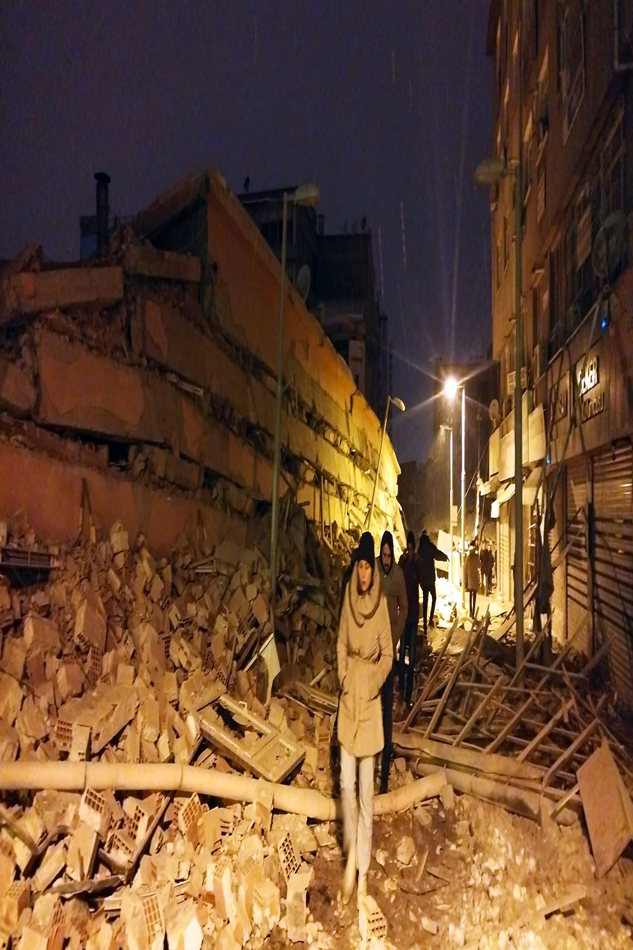 People walk next to buildings destroyed by earthquake.