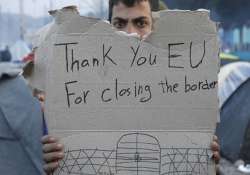 A refguee holds message, “Thank you EU for closing the border” during a protest