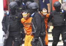 Indonesian police officers escort suspected millitants