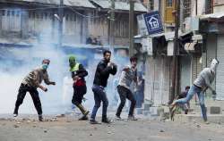 Protesters throw stones on police amid tear smoke during a clash in Srinagar