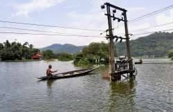 A villager uses a boat to cross flood water in Rajabari village in Kamrup dist