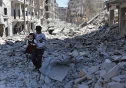 A Syrian man holding a girl as he stands on the rubble of houses in Aleppo. 