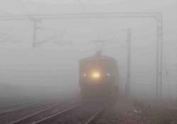 A train moves slowly amid a thick blanket of fog on a cold morning in Delhi