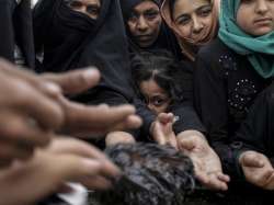 Mosul residents reach out for baked cookies at a food distribution point 