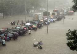 People walk along a flooded street during heavy rain showers in Mumbai