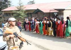 Voters wait in a queue to cast their votes during Himachal Pradesh assembly elections at a polling booth in Shimla