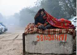 A homeless man sits wrapped in a blanket to protect himself from a cold winter morning in New Delhi.