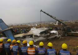 Nepalese rescuers and police are seen near the debris after a passenger plane from Bangladesh crashed at the airport in Kathmandu