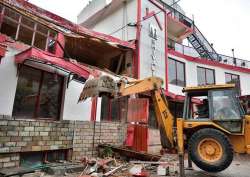 A demolition squad razes the illegal floor of a hotel at Dharampur near Kasauli in Solan