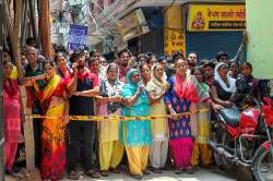 Neighbours stand near the house, where 11 members of a family- four men, three women and four girls- were found hanging from an iron grill, in Burari area of New Delhi on Sunday.