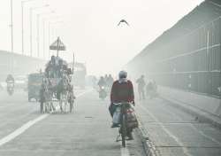 Commuters ride through heavy fog on a winter morning, in New Delhi