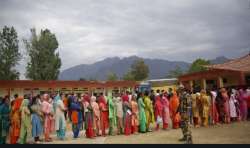 People wait outside a polling booth at Anantnag. 