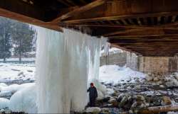 Srinagar: A man looks at icicles hanging from a bridge after snowfall at Tangmarg near Srinagar, Monday, Dec.30, 2019. (PTI Photo)