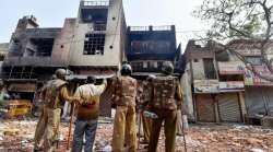 Security personnel look at houses set ablaze in the violence over CAA in parts of Northeast Delhi