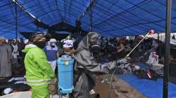 Paramilitary police officers in hazmat suit disinfect a tent built on a field where a mass congregat