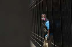 A man wears a protective mask while waiting for a bus in Detroit, Wednesday, April 8, 2020. As of mi