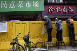 Residents climb on chairs to buy groceries from vendors behind barriers used to seal off a neighborh