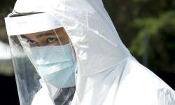 A Fraser Health healthcare worker makes his way through the parking lot at a drive-through COVID-19 