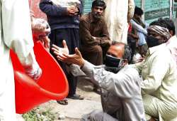 Daily wage laborers receive food distributed by a volunteer during a government-imposed nationwide l