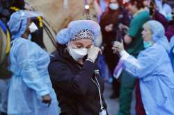 A medical worker reacts as police officers and pedestrians cheer medical workers outside NYU Medical