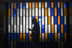 An elderly man wearing a mask plays with his smartphone at the lobby of a building in Caracas, Venez