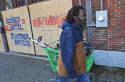 In this Tuesday, March 31, 2020 file photo, Vincent Amos, who identified himself as homeless, pulls a shopping cart with his belongings amid businesses closed by concerns of the COVID-19 coronavirus in the Deep Ellum section of Dallas. Amos said his shelter in place routine includes walking the area looking for work cleaning windows