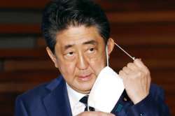 Japan's Prime Minister Shinzo Abe removes a face mask as he speaks at a press conference in Tokyo Th