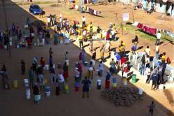 In this March, 31, 2020, photo, women and children wait for their turn to fetch water in a poor suburb of Harare, Zimbabwe. For people around the world who are affected by war and poverty, the simple act of washing hands is a luxury, even during the coronavirus pandemic. In Zimbabwe, clean water is often saved for daily tasks like doing dishes and flushing toilets. (AP Photo/Tsvangirayi Mukwazhi)
 