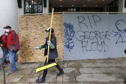 A woman helping to clean up downtown walks near graffiti Sunday, May 31, 2020, in Seattle, following