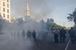 Tear gas floats in the air as a line of police move demonstrators away from St. John's Church across