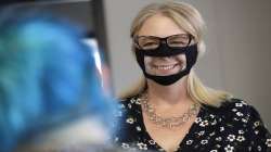 In this June 3, 2020, photo, Chris LaZich, of Fleet Science Center, wears a mask with a window as she talks with Delpha Hanson in San Diego. Face coverings to curb the spread of the coronavirus are making it hard for people who read lips to communicate. That has spurred a slew of startups making masks with plastic windows to show one's mouth. The companies are getting inundated with orders from family and friends of deaf people, people helping English learners see the pronunciation of words, and even hospitals that want their patients to be able to see smiles. Face masks with windows mean more than smiles to deaf people