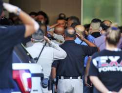  People salute as the body of a McAllen Police officer is carried out at McAllen Medical Center, Sat