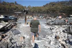 Artist Marcia Ritz, 77, leaves after looking through the rubble of her manufactured home at the Span