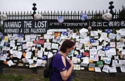 In this May 28, 2020, file photo, a woman passes a fence outside Brooklyn's Green-Wood Cemetery ador