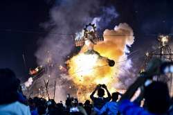 People look on as an effigy of demon king Ravana burns during Dussehra festival, at Karkardooma in New Delhi, Sunday, Oct. 25, 2020.