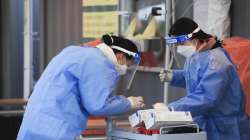 Medical workers wearing protective gear prepare for a coronavirus test at a coronavirus testing site